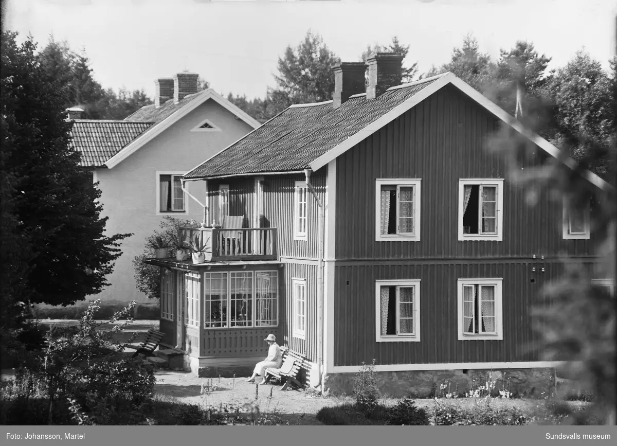 Två bilder av en bostadsbyggnad med glasveranda. På en bänk sitter en kvinna i ljus dräkt och hatt. Den ljusa byggnaden bakom är samma som SuM-foto034836, Villa Göta. Okänt var i Sverige bilden är tagen.