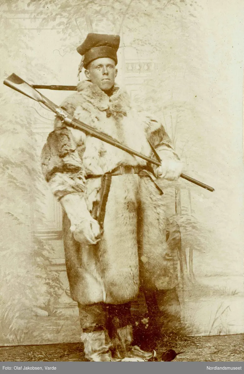 Portrett av ukjent mann kledd i pesk, skaller og samelue. Han har gevær og samekniv.