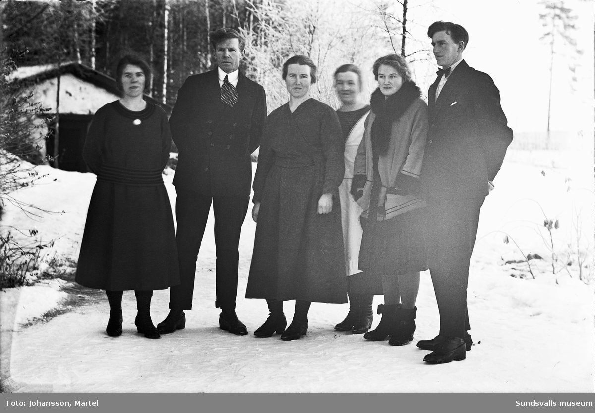 Gruppbild vintertid med från vänster: Johanna "Hanna" Johansson, Gustaf Persson, Märta Johansson, Sigrid Persson samt två oidentifierade personer. I bakgrunden syns jordkällaren på Brännsvedjan, Sörfors.