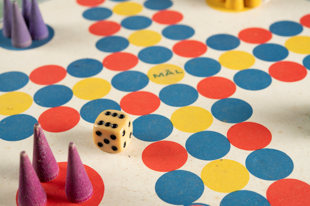Spel i originalförpackning av papp, med spelplan, instruktioner, tärning och spelpjäser. En spelpjäs saknas. Förpackningen är en kvadratisk, platt ask i ljusgrön, bleknad färg med text på framsidan. Spelplanen är formad som ett kors, bestående av tre rader med prickar för spelpjäsernas placering, i fyra olika färger. I varsitt hörn är spelarnas "bo" markerat, där deltagarna startar, vart och ett i varsin färg; rött, blått, gult och grönt.