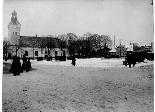 Varbergs torg med ett fåtal torgbodar och kyrkan vintertid under tidigt 1900-tal.