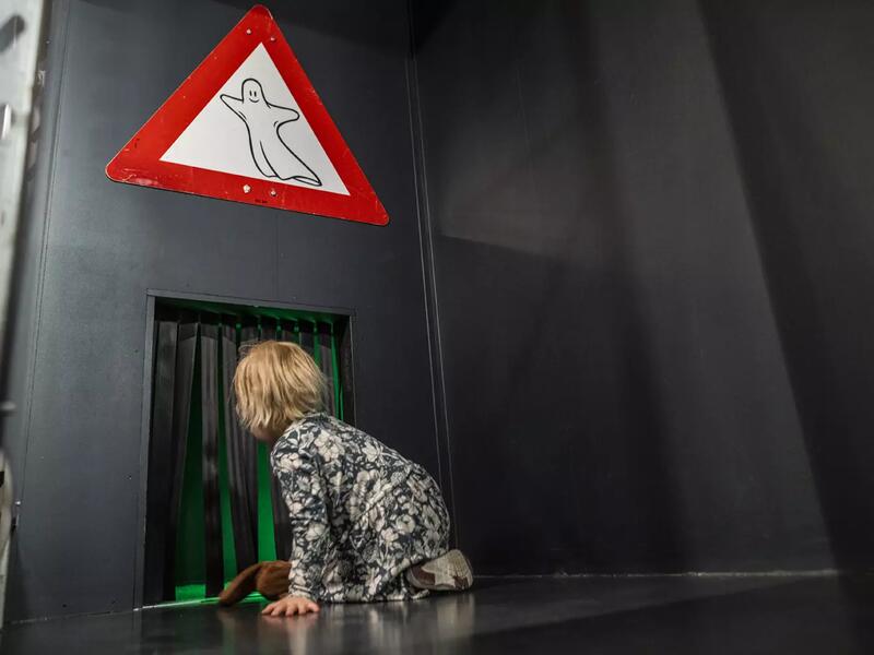 Bildet viser et barn på vei inn i Spøkelsestunnelen i utstillingen Drift.