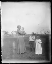En kvinne og tre barn i landlige omgivelser