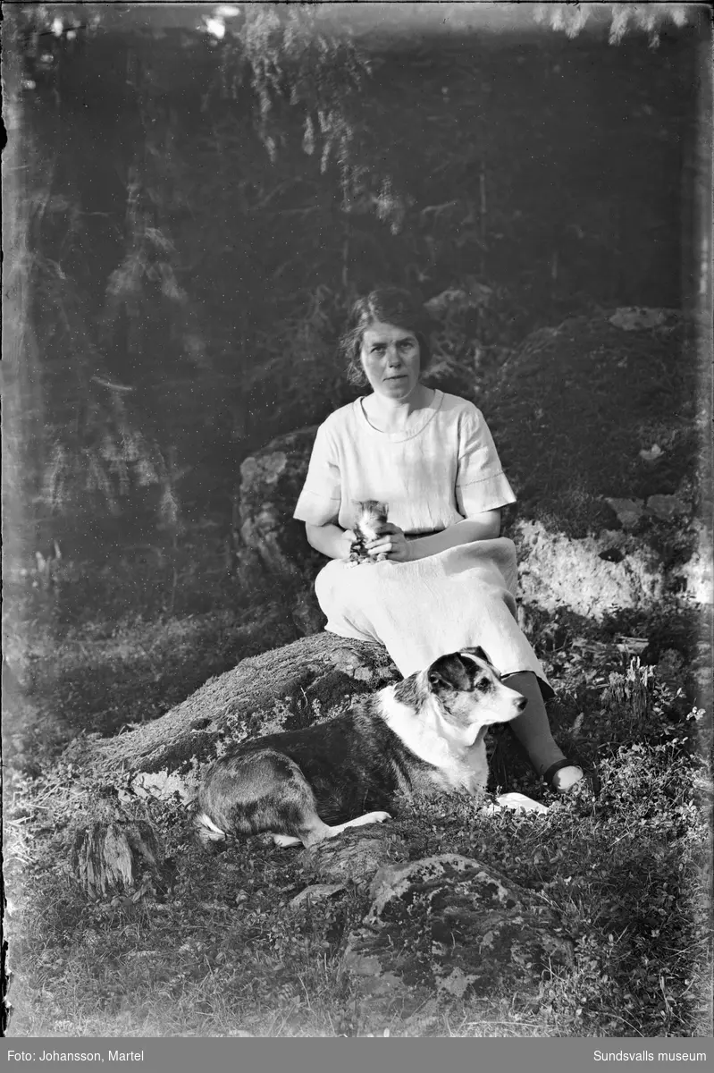 Porträttbild av Johanna "Hanna" Johansson, Sörfors, i skogsmiljö med en hund vid fötterna och en kattunge i famnen.