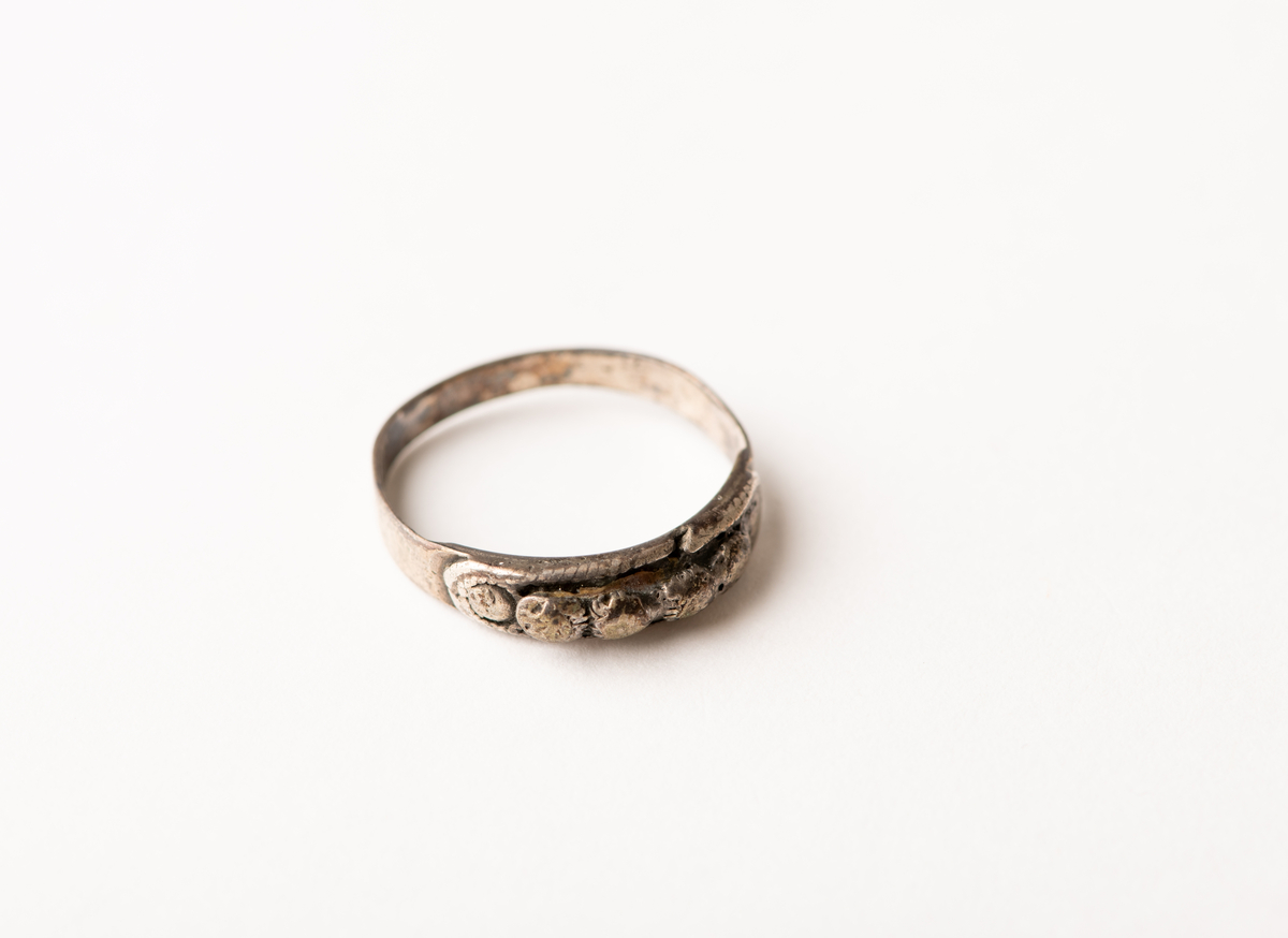 Tynn båndformet ring med påloddet plate med fire sølvperler, flankert av to flatere.