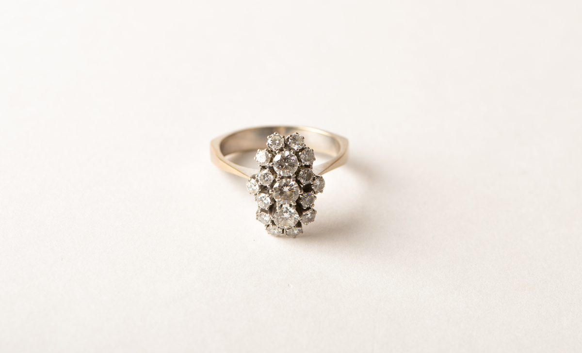Stor briljantring i hvitt gull med knippe av kronefattede briljantslipte diamanter, 3 stk. 5 mm diam, omgitt av 14 mindre.
