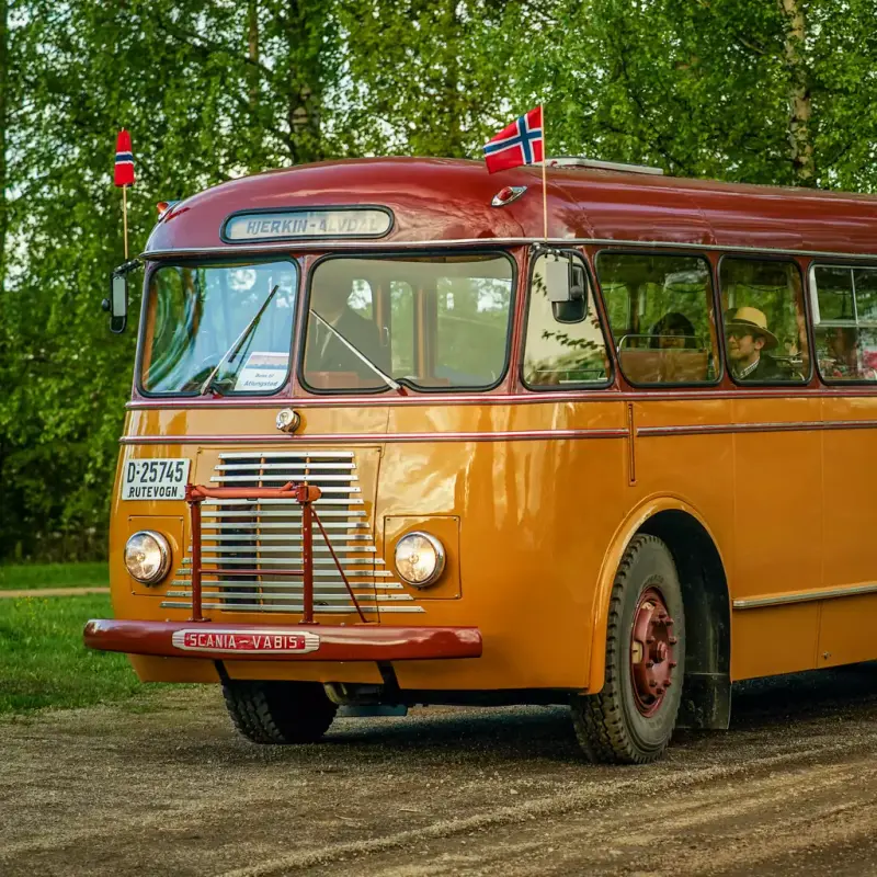 Bilde av gul og rød veteranbuss med det norske flagg på sidene