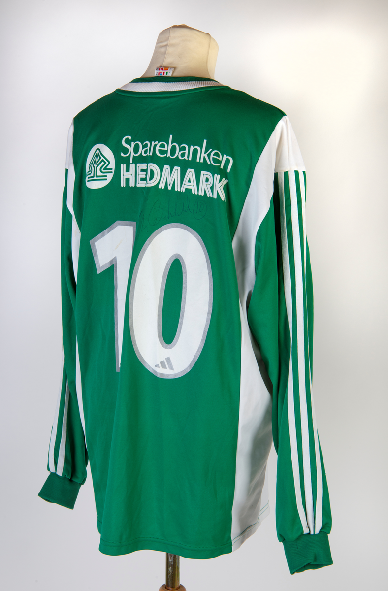 Langermet fotballtrøye nr. 10, Hamarkameratene, signert spiller Frode Birkeland. Ellers dekket av firmanavn/sponsorer. Hamkamfargene grønt og hvitt.