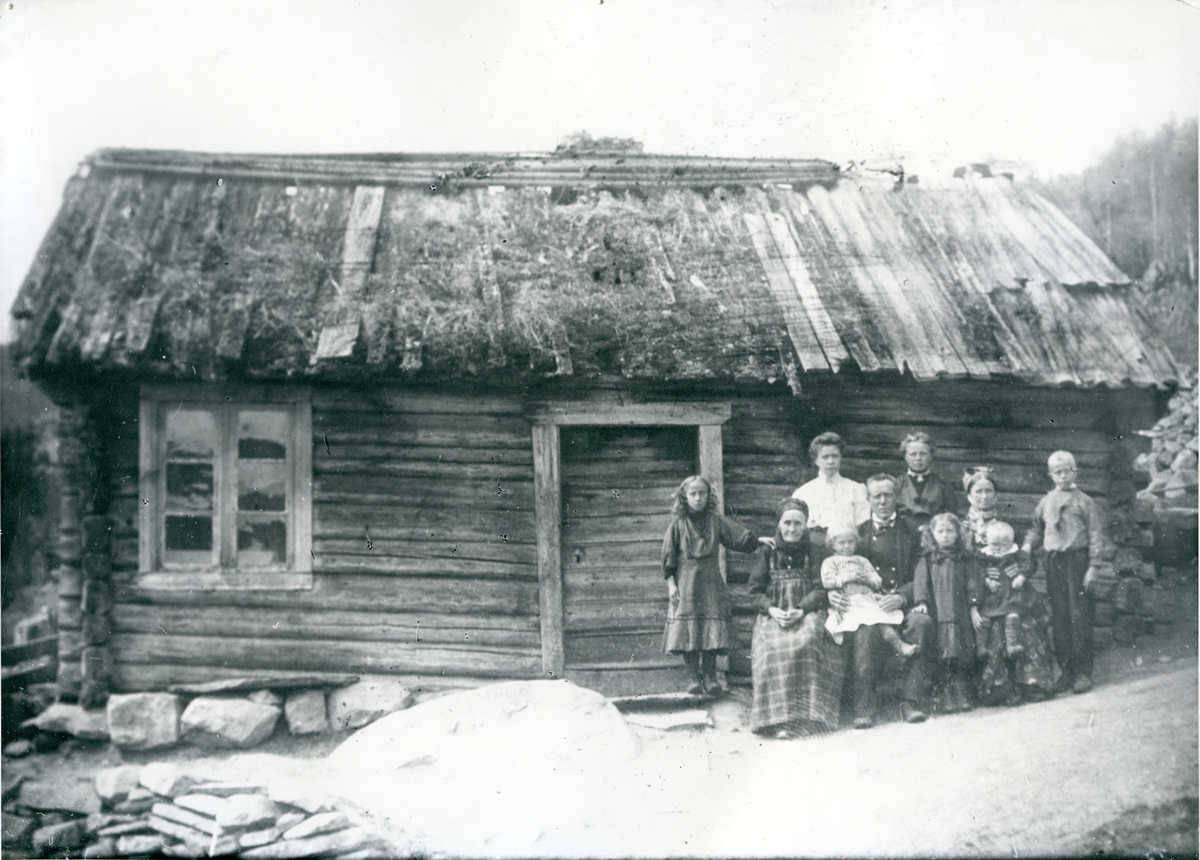 Familen Jordesplass foran gammel hallingstugu.
