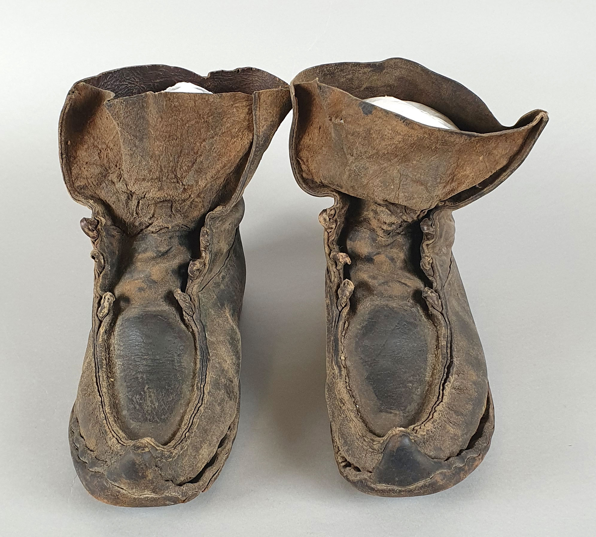 Et par støvler av skinn. Skinnet er sydd sammen på framsidene. Støvlene er påsatt halvsåle av lær og hæl av lær og gummi.