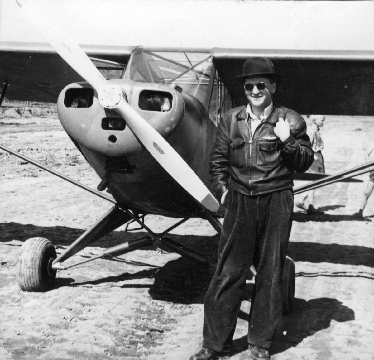 En mann står ved siden av et lite fly. Dette flyet var det første flyet som landet på Røros flyplass