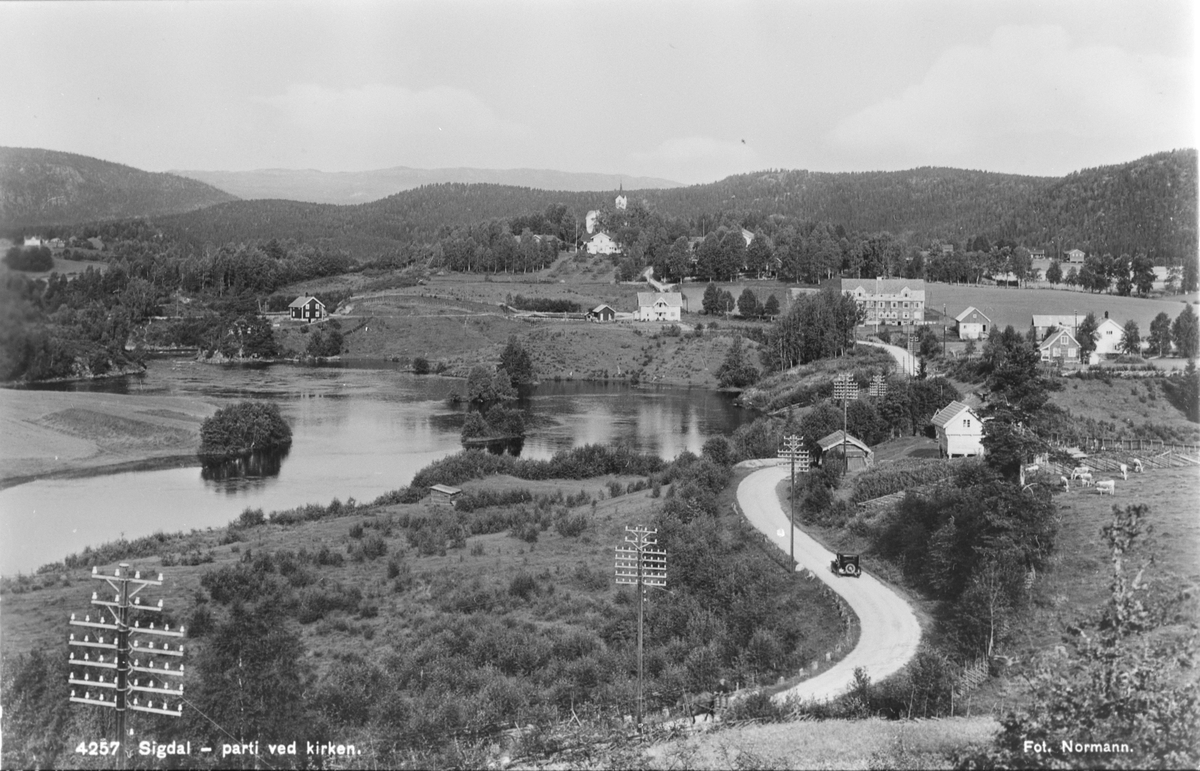 Prestfoss med landeveien langs Simoa, Holmen kirke og Sigdal gamlehjem (nåværende Folkemusikksenteret i Buskerud). Postkort fra ca. 1935.
