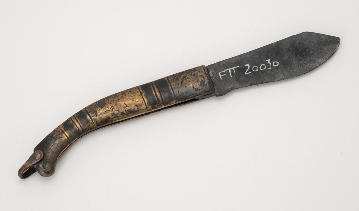 Foldekniv med messingskaft og blad av stål/jern. Skaftet har graverte ranker. På enden av skaftet er det en hempe av kobber.