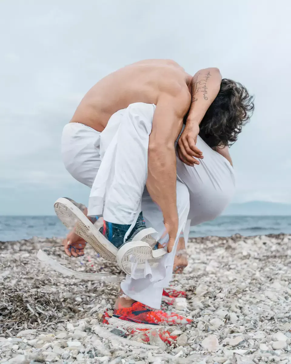 To menn trener kampsport på en steinstrand, bildet er delvis dobbelteksponert slik at vi blir usikker på om det er ett eller to mennesker.