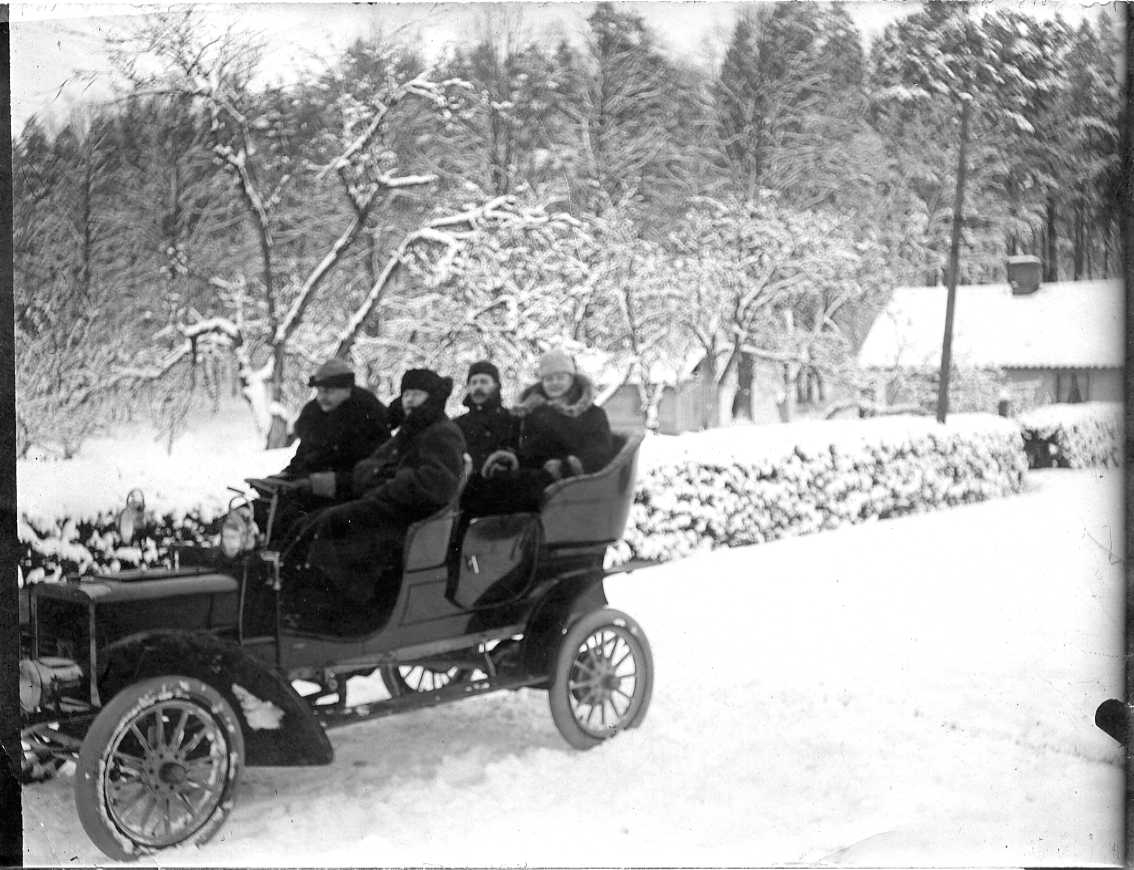 Fyra vinterklädda män i en öppen bil i ett vinterlandskap.