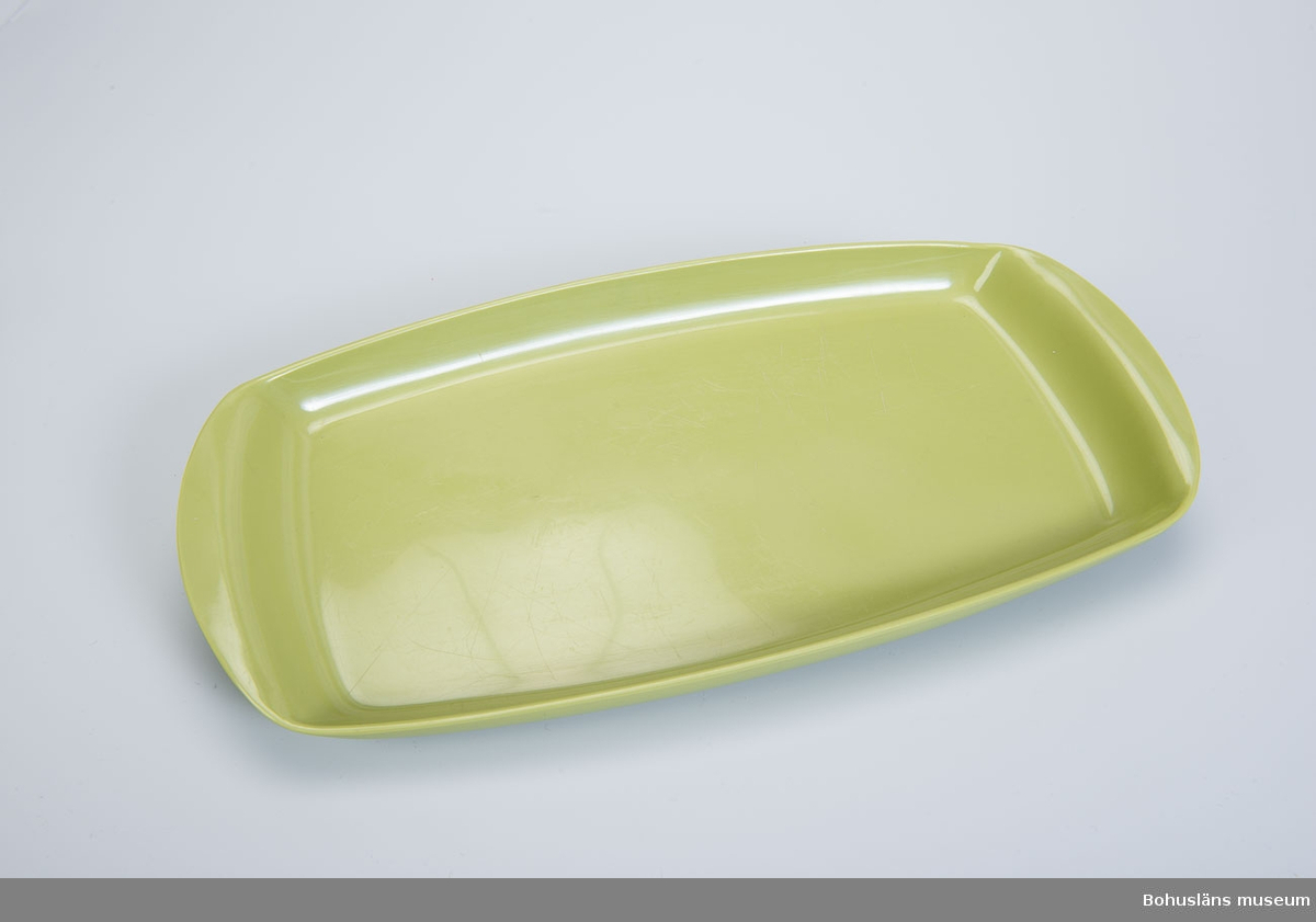 Rektangulärt lågt serveringsfat eller uppläggningsfat med rundade  handtag i ljusgrön melaminplast.
