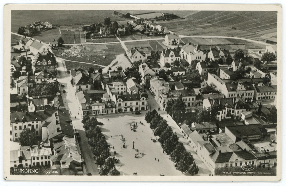 Vykort med flygfoto över Stora torget, Källgatan och Torggatan, Enköping. Försvarsstaben godkände detta vykort för försäljning den 4/6- 1940, så motivet fotograferades någon gång innan detta datum.