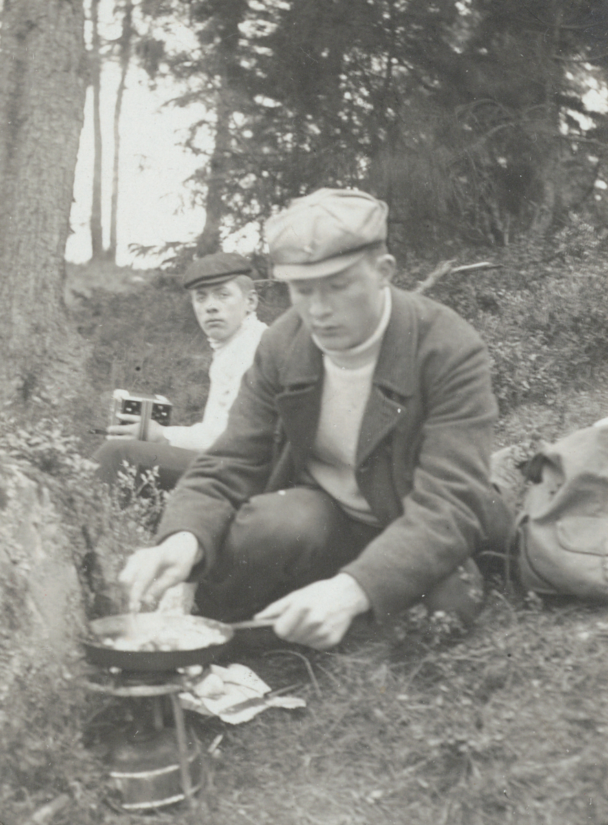 Två kanotister på utfärd i skärgården. I förgrunden lagar Ragnar Högborg mat på ett stormkök. I bakgrunden en FKI-kamrat (namn okänt) med lådkamera i handen.