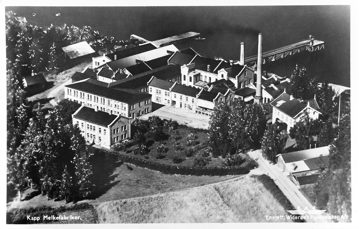 Flyfoto av Kapp Melkefabrikk en gang på 1930-tallet. Direktørboligen (med flagg) til høyre brant i 1944.