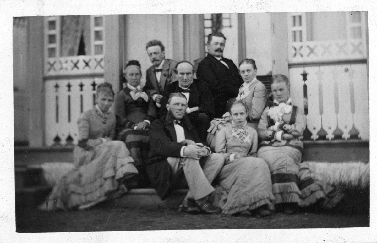 Foto av gruppe på terasse på Dal Gård i 1879. Antagelig familien Faye/Dahll. Lege Oscar Platou sitter helt til venstre i bakerste rad. Sigrid Faye helt til venstre i første rad