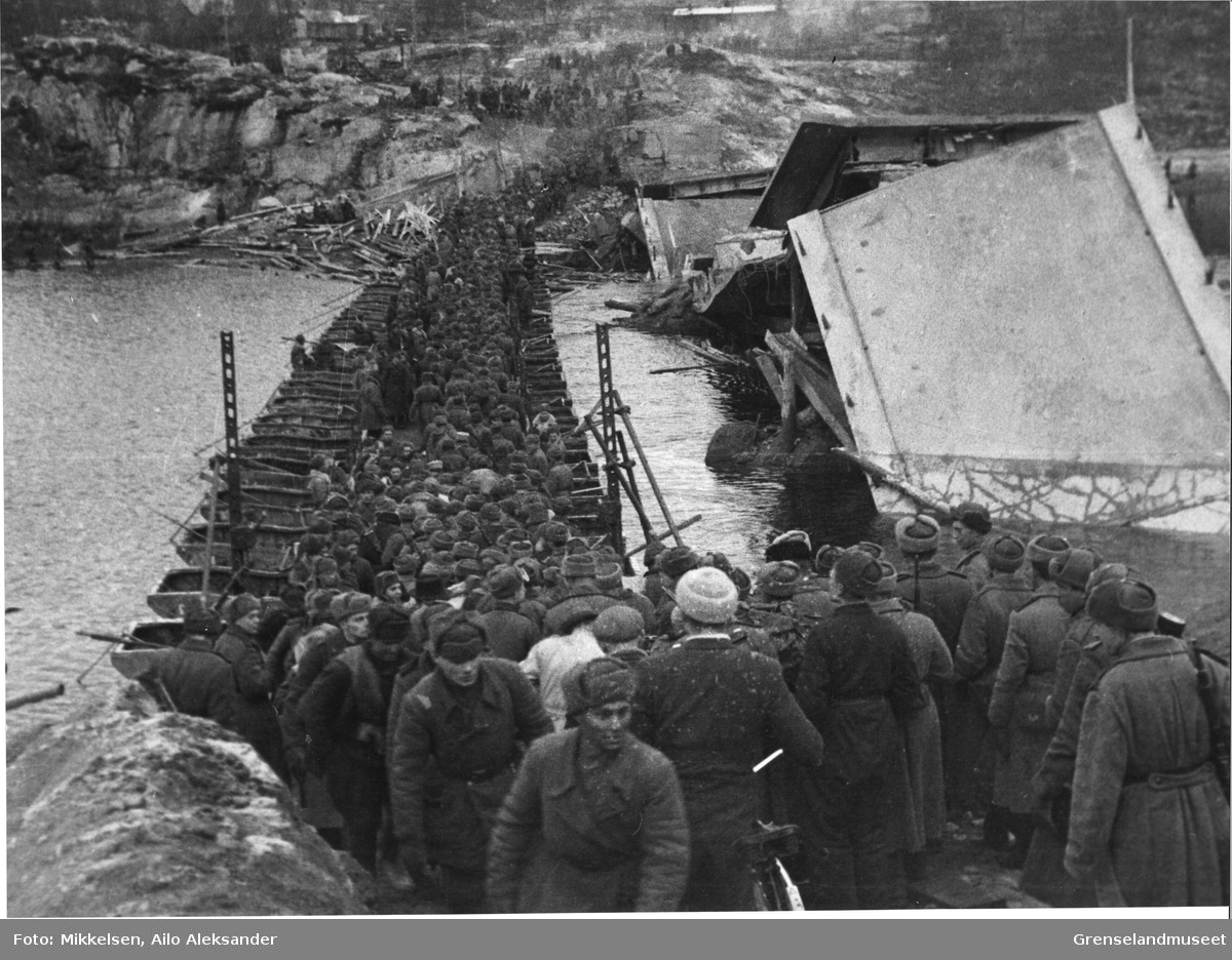Sovjetiske soldater krysser Pasvikelva over en improviser bru ved siden av den sprengte brua ved Nyrud. Hendelsen fant sted i Pasvikdalen i Sør-Varanger kommune, høsten 1944.  