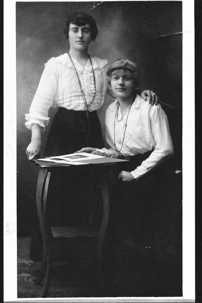 Portrett av 2 damer med  skjørt,bluse og smykker.