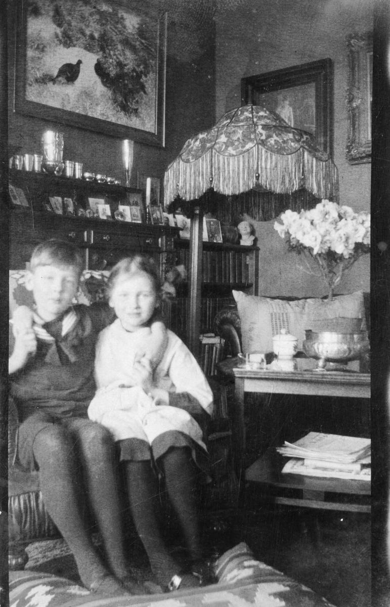 Foto av to barn som sitter i en stol. Niels Fredrik Aall og søster Cecilie Aall?