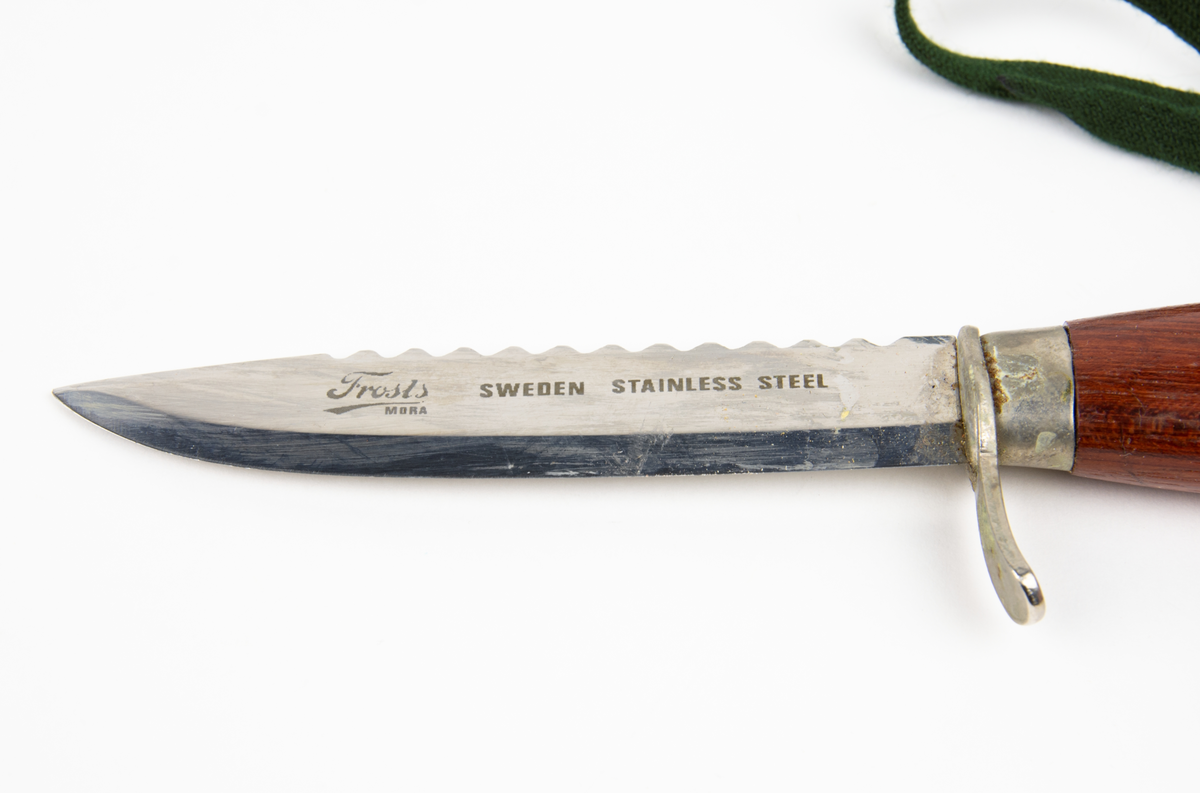 Slidkniv med rostfritt blad, träskaft, parerstång och slida tillverkad av unika. I kniven sitter en grön textilrem.