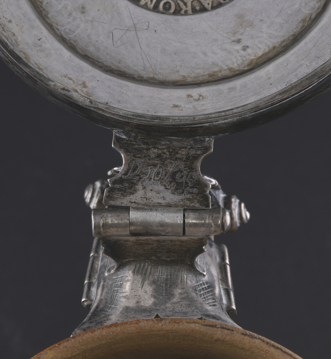 Krus av keramikk, med lokk av sølv. Kruset er farget oransje, hvorpå nederste del av korpus og håndtak er mørkere farget. Øverst og nederst på kruset er det dekorative riller. Hankfeste av sølv, med stående palmett. Lokk av sølv, med en tysk sølvdaler fra perioden 1620-1638.