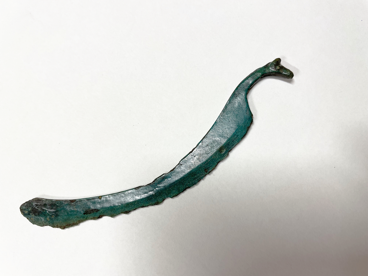 Svängd rakkniv av brons med hästhuvudformat handtag.