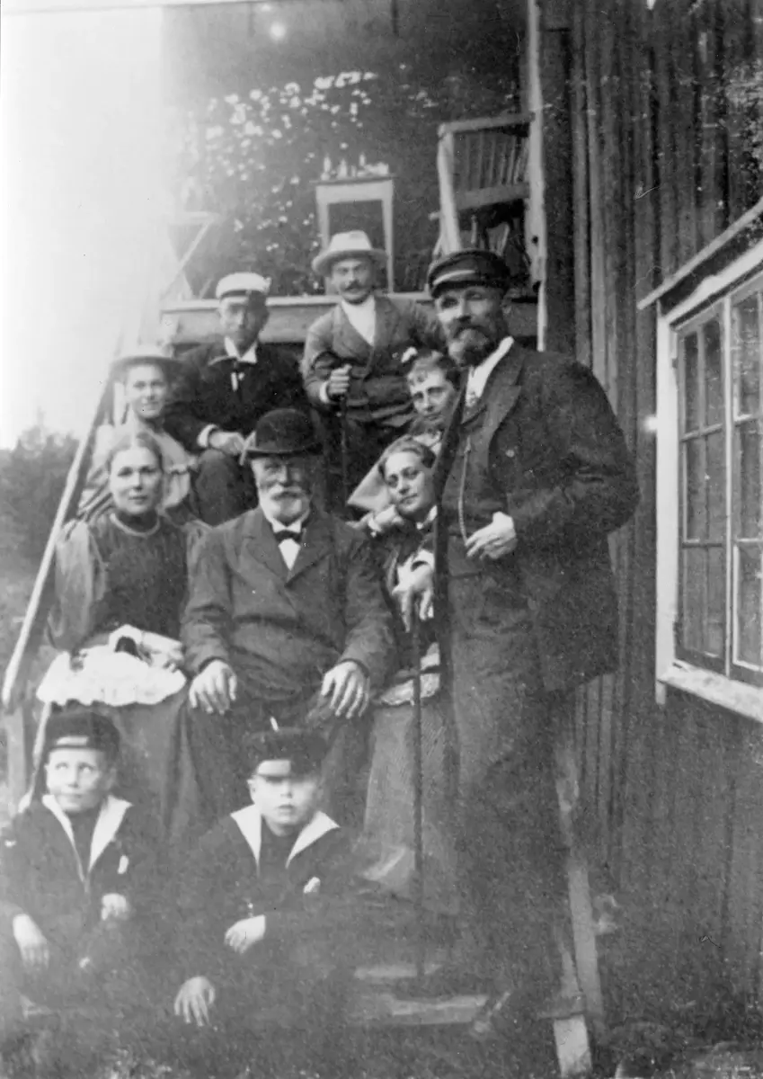 Gruppbild på trappan till övervåningen på Augustendal med far och son Silfverhjelm samt familjen Salomonsson med sönerna Carl och Otto längst ned. Två bilder.