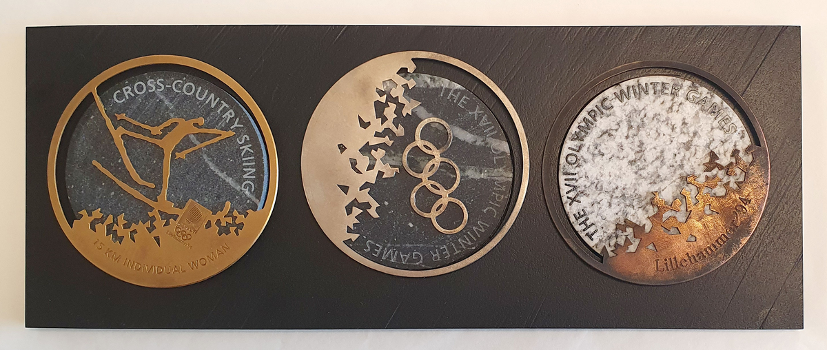 Utast til medaljer for Lillehammer '94. En gull-, en sølv- og en bronsemedalje på granitt, uferdige. Ligger på treplate.