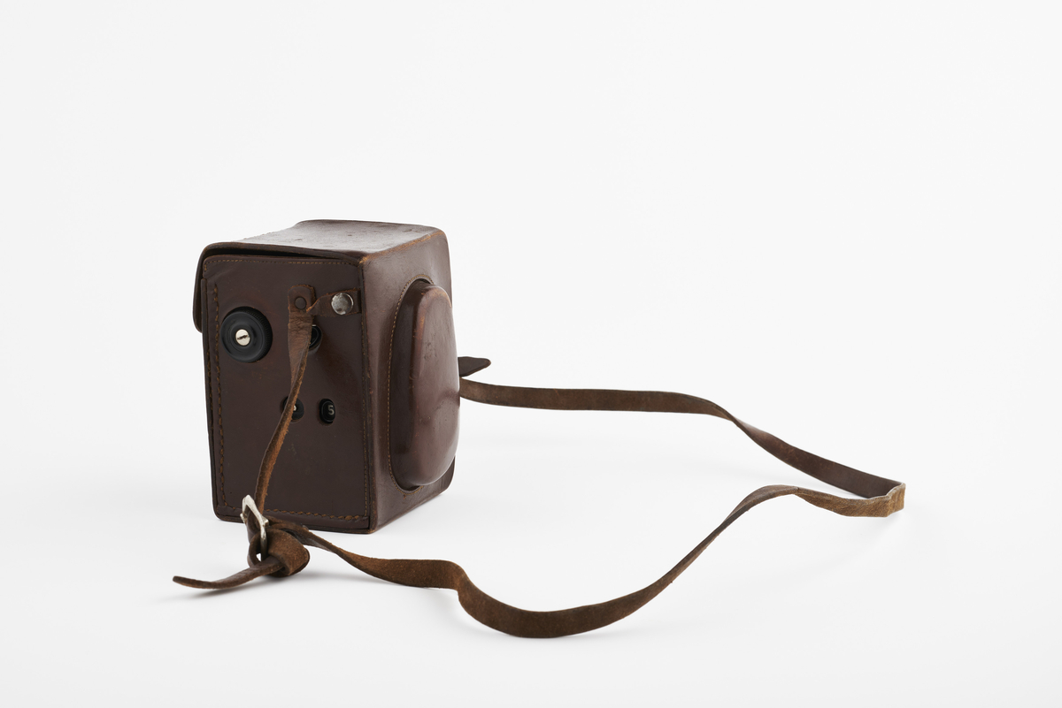 Kamera med tilhørende futteral/veske i brunt lær. Kameraet er av modellen Voigtlander Brillant, produsert på 1930/40-tallet. Det har en Compur-Rapid Anastigmat Voigtar 1:3,5 7,5cm linse. 
Plassert inne i kameraet er en snorutløser og en bruksanvisning til eksponering som har tilhørt et annet type kamera, men trolig brukt som en huskelapp for fotografen.

Samlingen består av diverse fotoutstyr og andre gjenstander som har tilhørt Synnøve Brændshøi sitt fotoatelier. De fleste er nok fra 1940- og 50-tallet.