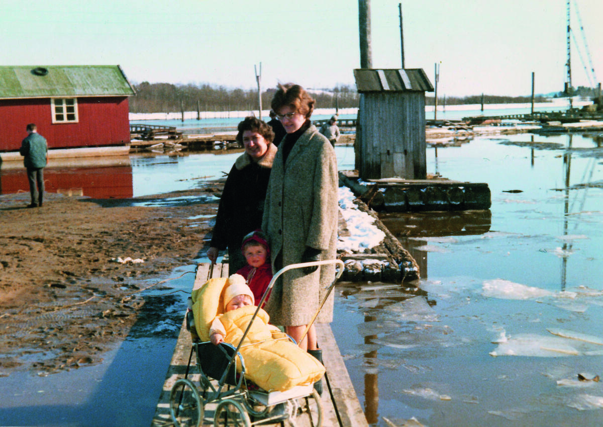 Fotografi av to kvinner og to barn som står på en flåtegang ute på fløtingsanlegget på Fetsund lenser