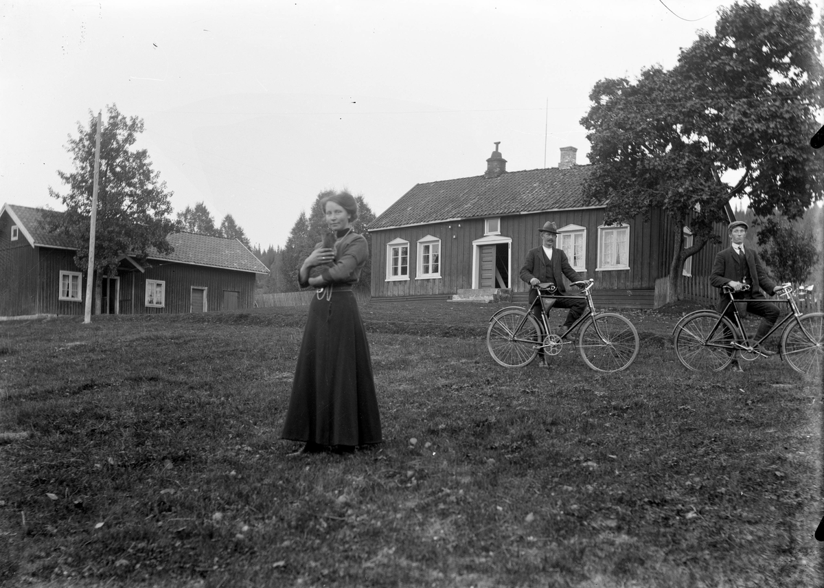 Gårdsmotiv, portrett av kvinne med kattunge og to menn med sykkel. TIl høyre en av Stendalen guttene 

Fotosamling etter fotograf og skogsarbeider Ole Romsdalen (f. 23.02.1893).
