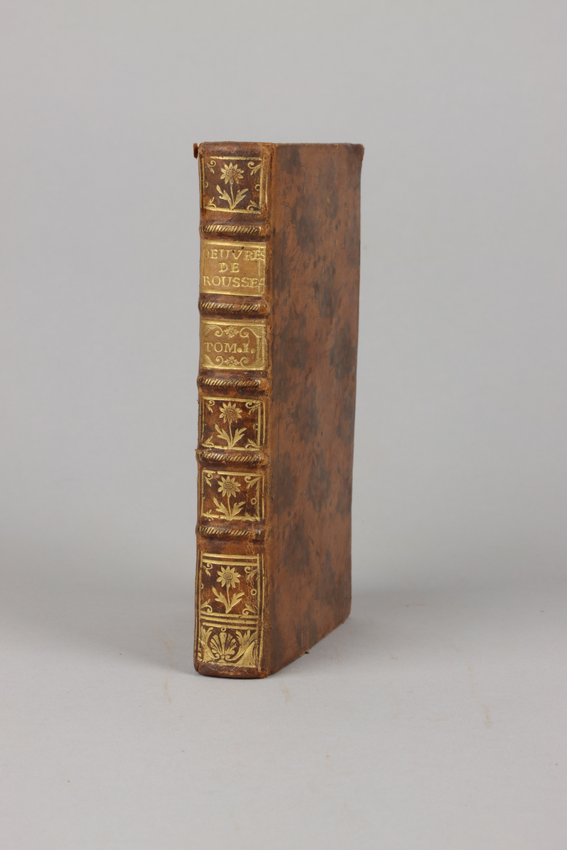 Bok bunden i helfranskt band, pärm i ljust mönstrat läder. Rygg med guldpräglingar och fem upphöjda bind, rött snitt samt dekorerad med stiliserade blommor och musslor. Titelsida "Oeuvres de Rousseau", nouvelle édition, del 1.
