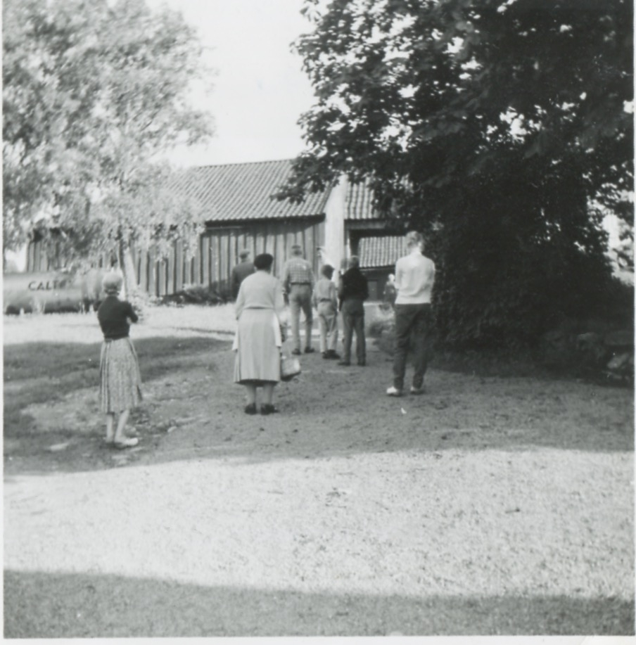 En grupp människor står på gårdsplanen och tittar på huset, Backen eller Högen (övre gården) 1960-tal.