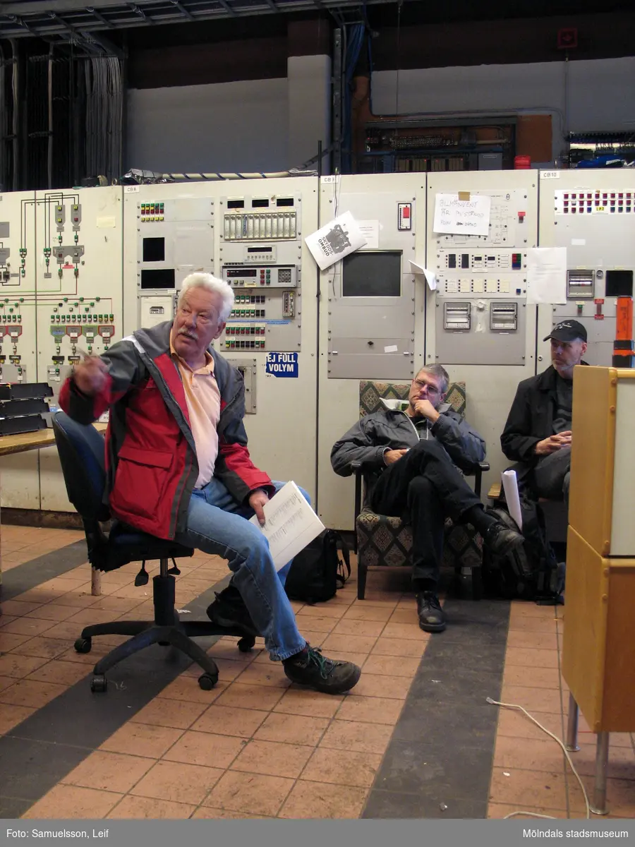 Tre män sitter i ett kontrollrum. Interiörfotografi från byggnad vid Soabs industrianläggning i Mölndals Kvarnby, år 2007. Anläggningen användes vid fototillfället av Hexion Speciality Chemicals Sweden AB.