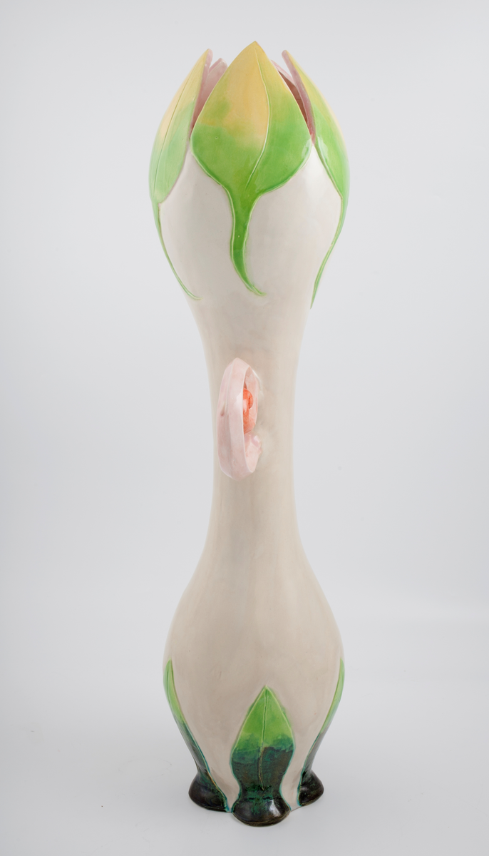 Vase i glasert steingods. Vasen er formet som en tulipan eller en lignende floral form. Toppen og bunnen av vasen har grønne blader, integrert i selve vasen. Vasen er hvit med rosa, spiralformede hanker.