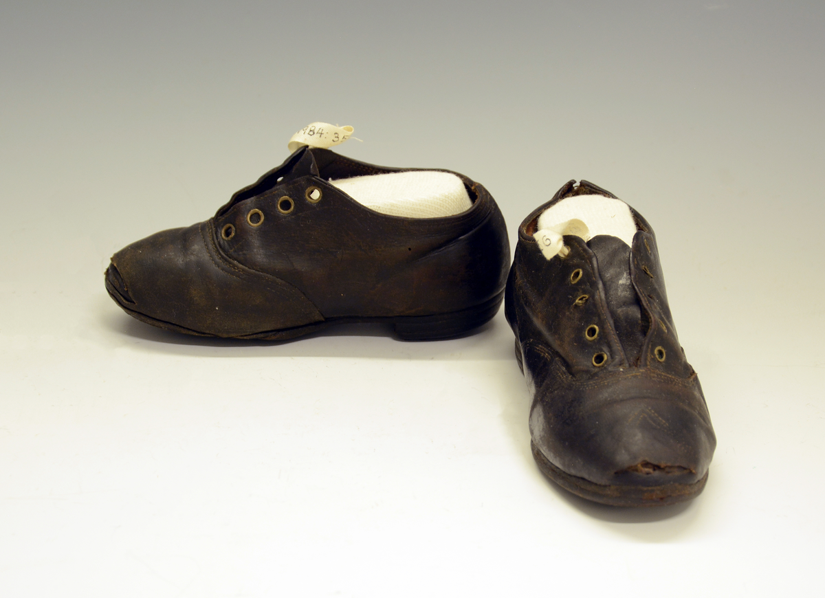 Barnesko.1 stk sko i brunt lær med 5 stk snørehull med metallmaljer. Jernstifter i hæl og treplugger i sålen.