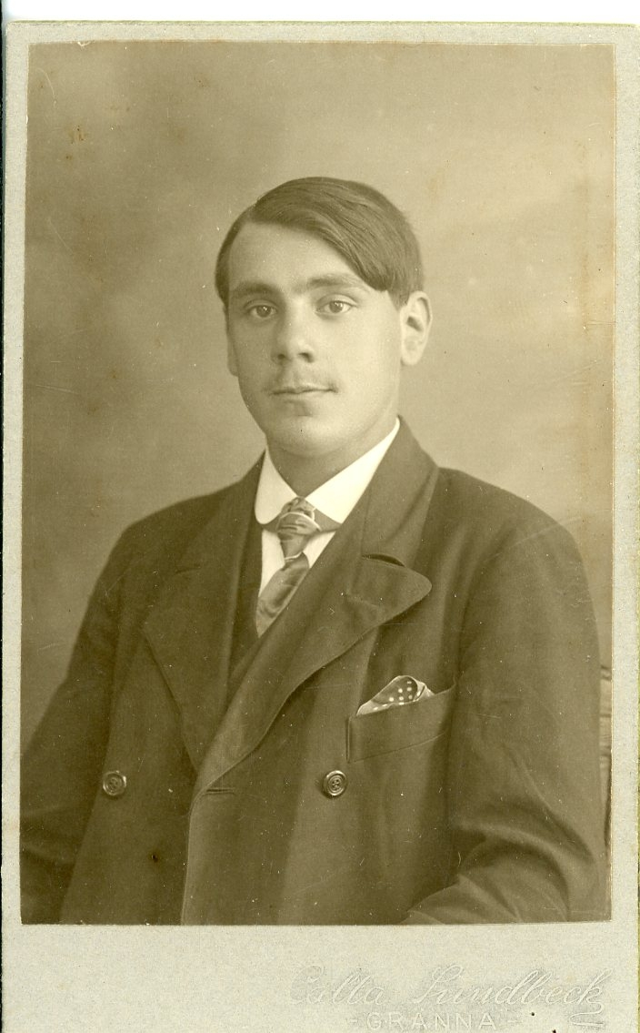 Porträtt av en okänd ung man med slips och näsduk i fickan.