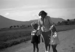 Kvinne med to barn på en landevei. Det er ukjent hvem vi ser