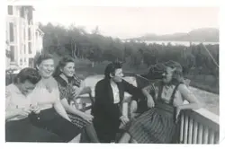 En gruppe kvinner sitter på på terrassen utenfor en bygning 