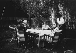 Fem personer rundt kaffebordet ute.