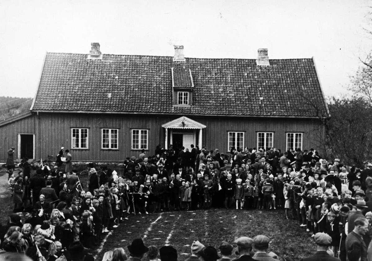 17. mai feiring på Huseby 1946. Oppstilling foran våningshuset. Det er en åpen plass midt i folkemengden, kanskje en bane for lek?