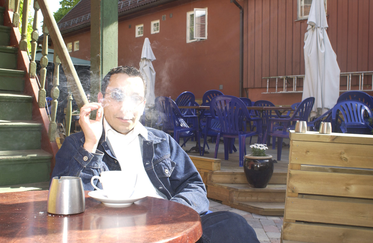 Pubgjest sitter ved et bord med røyk og kaffe i bakgården Milde Moses Pub & Spiseri i Drøbak
