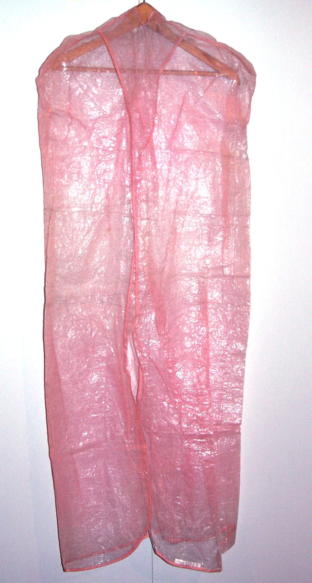 Gjennomskinnelig draktpose i rosa plast.Posen er i vevet materiale. Posen er sydd med omslag i toppen med hull til kleshenger. Kantet med skråbånd.