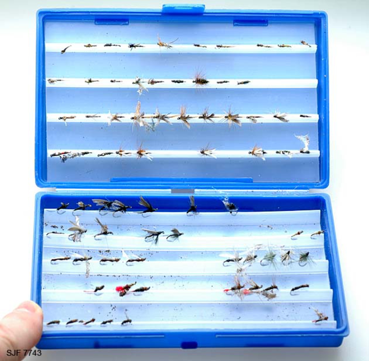 Tilstand: I forbindelse med omfotografering av gjenstander høsten 2002, oppdaget OT Ljøstad at fluene i denne esken var langt på veg ødelagte av møllangrep.  Problemet skyldes at gjenstanden har vært lagret i magasin C, der temperaturen er såpass høy at møllen trives. 
Boksen inneholder ialt 75 stk tørrfluer. Tørrfluene har den funksjon at de flyter på vannet, derfor så bustete. En meget fin boks som en setter fluene fast i, istedenfor at de ligger hulter i bulter. Giveren har skrevet ei bok med navnet "Isfiske" sammen med Knut Rom, boka ble utgitt i 1972. Giverens far var en ivrig sportsfisker og ble gitt tittelen "Den fullendte sportsfisker". 

Boksen inneholder ialt 75 stk tørrfluer. Tørrfluene har den funksjon at de flyter på vannet, derfor så bustete. En meget fin boks som en setter fluene fast i, istedenfor at de ligger hulter i bulter. Giveren har skrevet ei bok med navnet "Isfiske" sammen med Knut Rom, boka ble utgitt i 1972. Giverens far var en ivrig sportsfisker og ble gitt tittelen "Den fullendte sportsfisker". 
