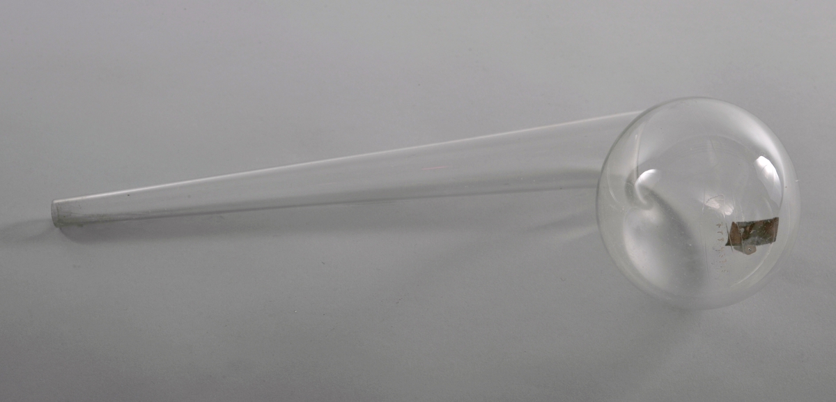 En dråpeformet kolbe av glass med et vinklet smalende rør som utløp. På utsiden av bøyen er det et utløp med propp av glass.
