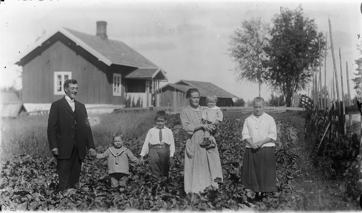 Familien Arnesveen oppstilt i hagen foran plassen de bodde. Fra venstre: Ole Arnesveen, Asbjørn Arnesveen, Arne Arnesveen, Mathea Arnesveen med datteren Agnes Arnesveen på armen. Lengst til høyre står Mathea sin søster Ottine.